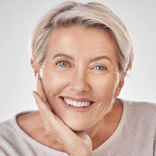 Older lady wearing invisalign clear aligners smiling at the camera.