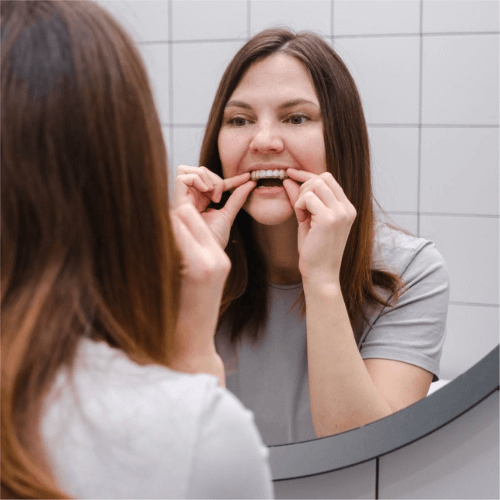 a woman placing in her Invisalign aligners