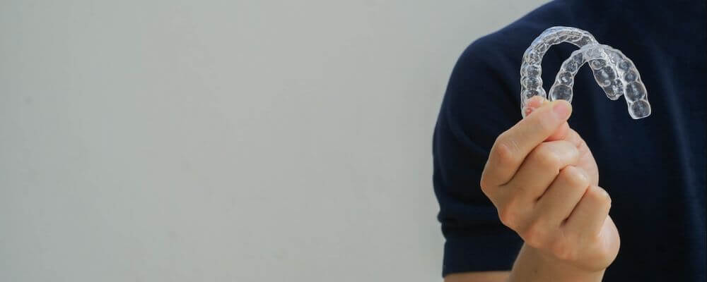 man holding Invisalign clear aligners 