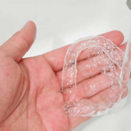 man cleaning his invisalign clear braces with water