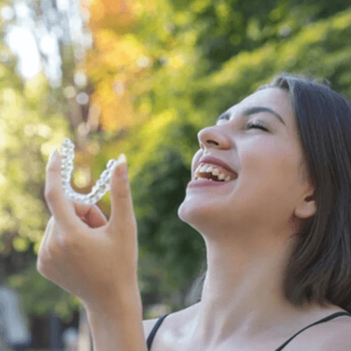 Woman holding invisalign aligners with a straight smile