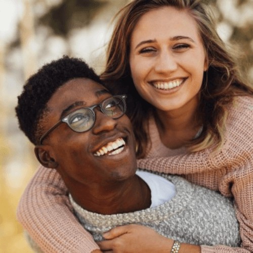 male and female with nice white smiles after completing their invisalign treatment.