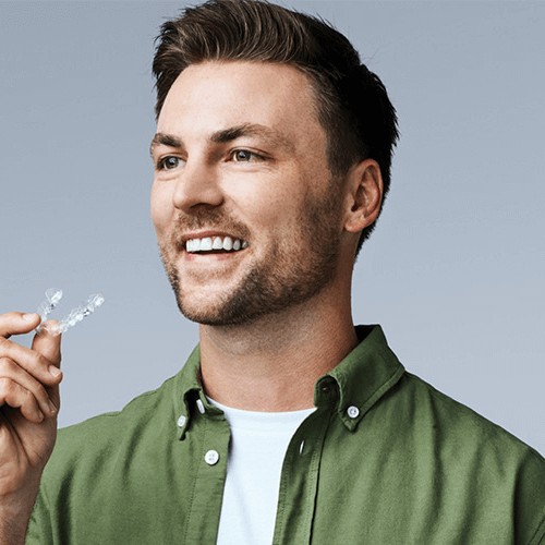 man holding Invisalign clear aligners smiling