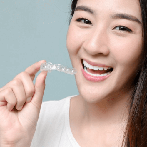 woman holding invisalign clear aligners in heaton mersey orthodontic clinic