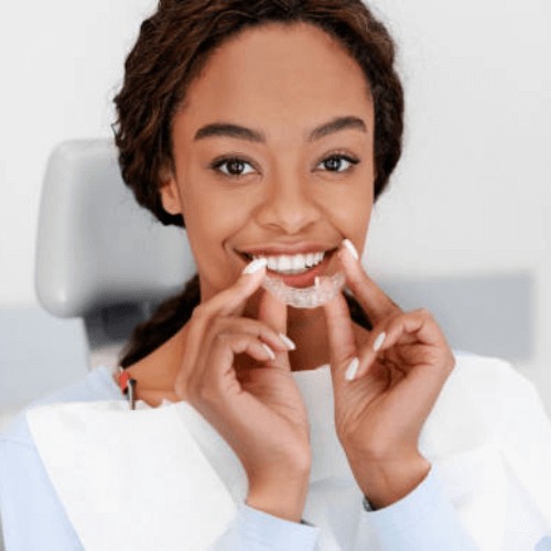 woman smiling holding her clear aligners / brace (invisalign) in Stockport, manchester