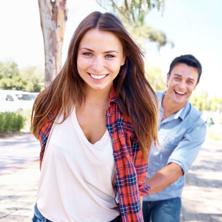 teen girl with straight teeth and white smile after Invisalign aligners with a man behind her.