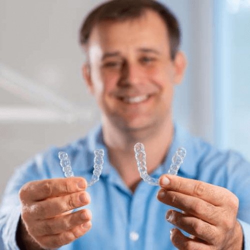 man holding invisible invisalign braces and smiling in Manchester, Stockport