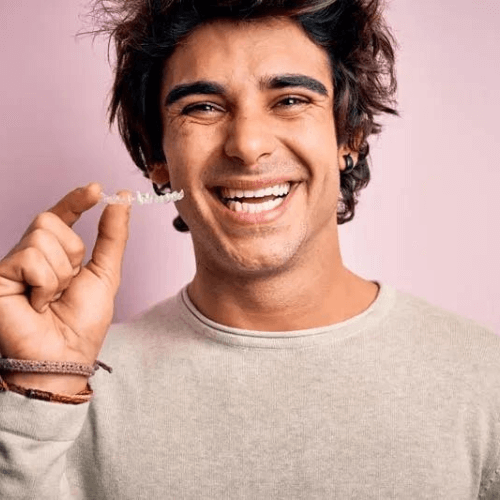 man smiling whilst holding clear invisalign aligners in Stockport