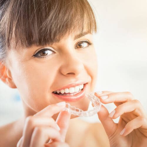 woman holding invisalign clear braces, manchester