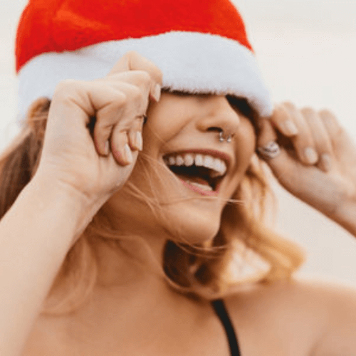 woman with perfect, straight and white teeth after having Invisalign Stockport smiling over christmas with a santa hat